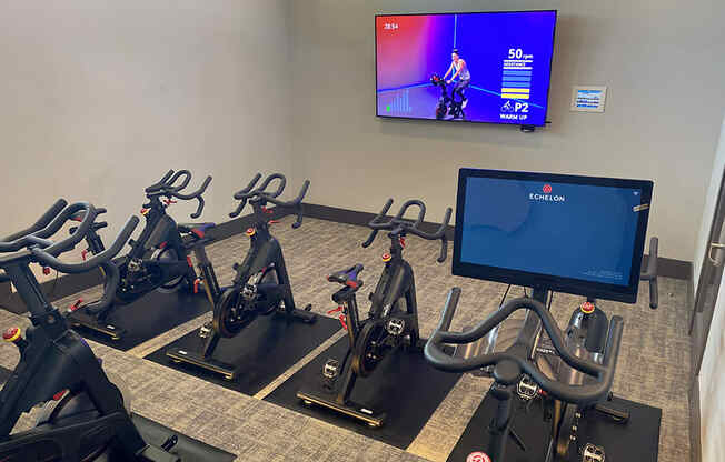 a row of exercise bikes in front of a tv