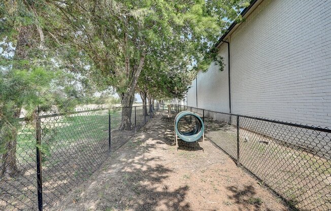 a large fenced in area with trees and a grassy area next to a building