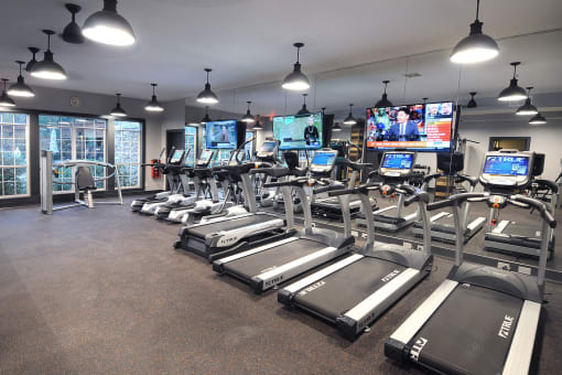 a gym with cardio equipment and televisions in a building