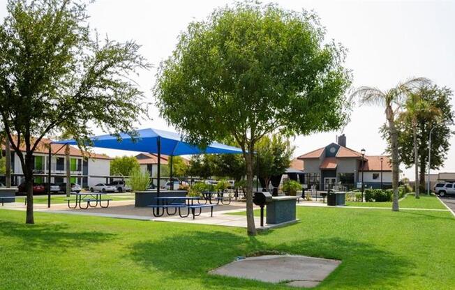 a park with tables and umbrellas and houses in the background