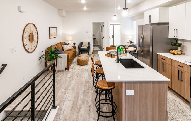 a kitchen and living room with a white counter top and a stainless steel refrigerator