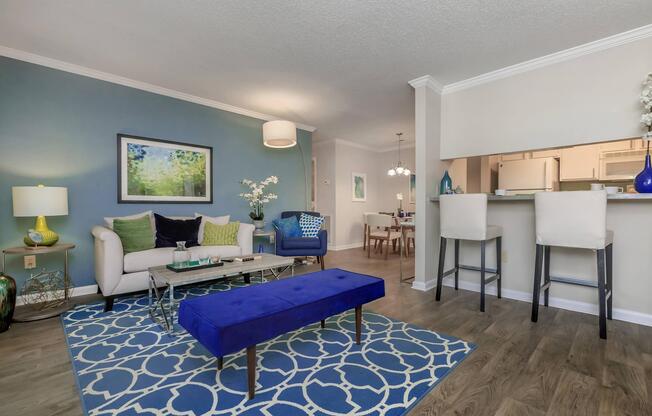 A furnished living room with a blue couch and rug at Ashley Oaks Apartments in Greensboro, NC