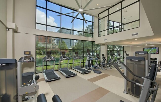 a gym with cardio equipment and windows