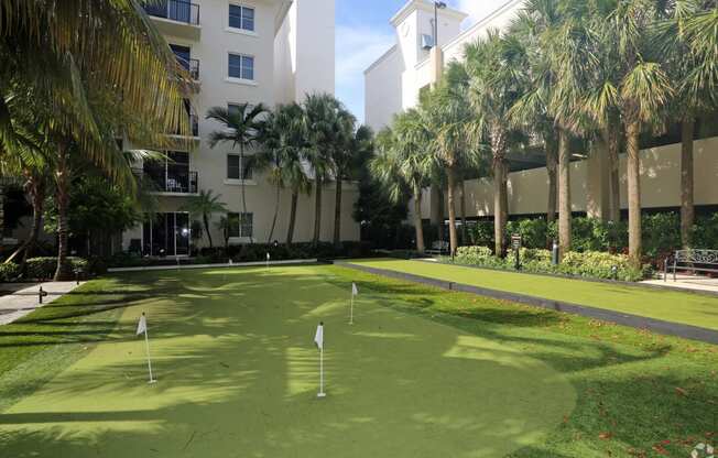 a golf course in front of a building with palm trees