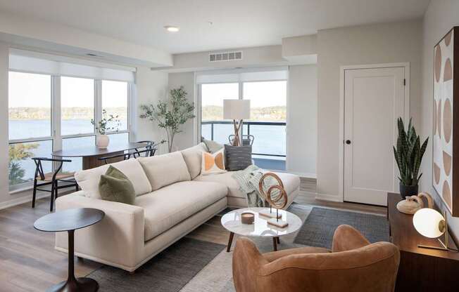 A living room with a white couch, a brown armchair, and a round table with a lamp on it.