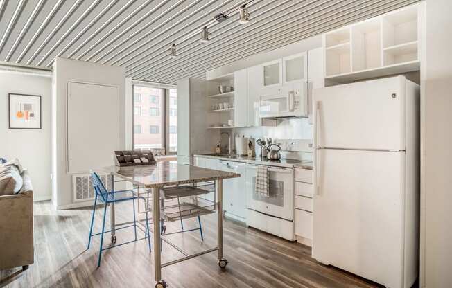 a kitchen with white appliances and a table with two stools