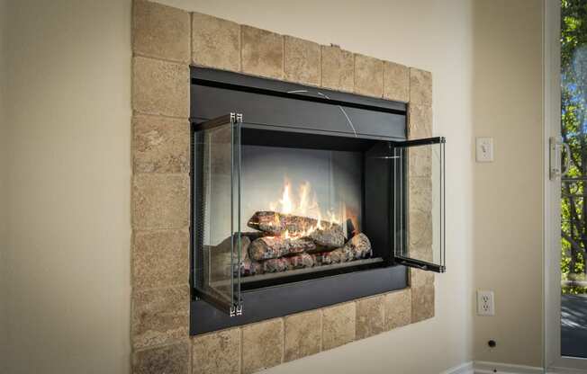 a fireplace with a glass door and rocks in the fireplace at The Village Apartments, Van Nuys California