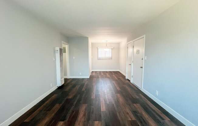 an empty living room with hardwood floors and white walls