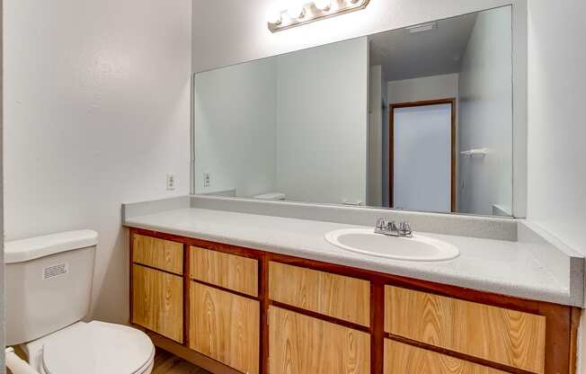 a bathroom with a toilet sink and mirror at Pacific Harbors Sunrise Apartments, Las Vegas, NV, 89142