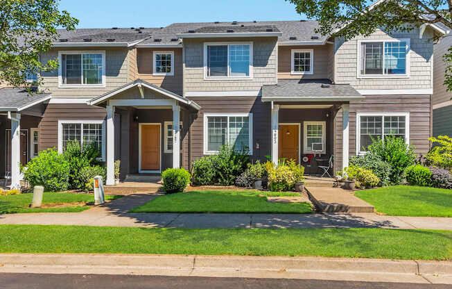 A row of townhomes with green lawns and trees in front at The Landing Apartments and Townhomes, Oregon, 97045