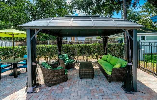 Poolside cabana at the Watermark Apartments in Lakeland, Fl with wicker patio seating with green cushions under large shade with bug nets.