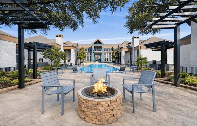 A fire pit sits in the middle of a patio with chairs around it.