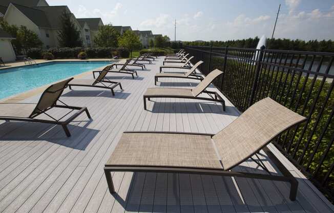 a large pool with chaise lounges on a sunny day