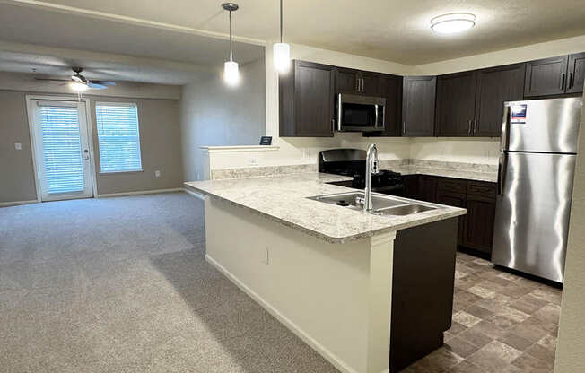 A kitchen with a breakfast bar and a living room at Andover Pointe Apartment Homes in LaVista, NE