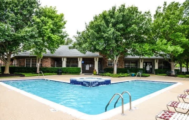 A swimming pool surrounded by trees and chairs.