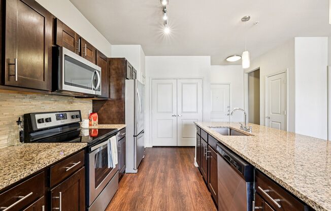 A kitchen with dark brown cabinets and granite countertops.