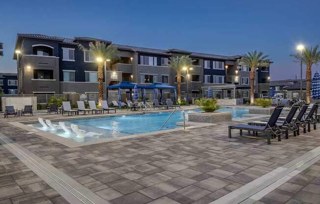 A large swimming pool surrounded by lounge chairs and palm trees. and cabanas