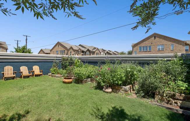 A lush garden with chairs and apartment buildings in the background at Encore at Buckingham Apartments in Richardson, TX