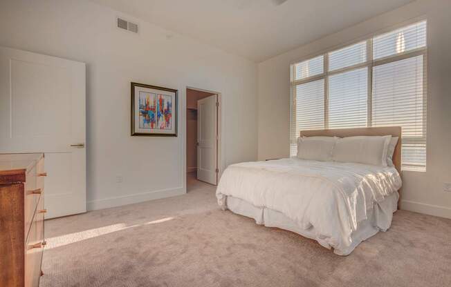 A bedroom with a large bed and a painting on the wall.