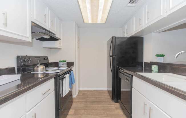 a kitchen with white cabinets and a black refrigerator