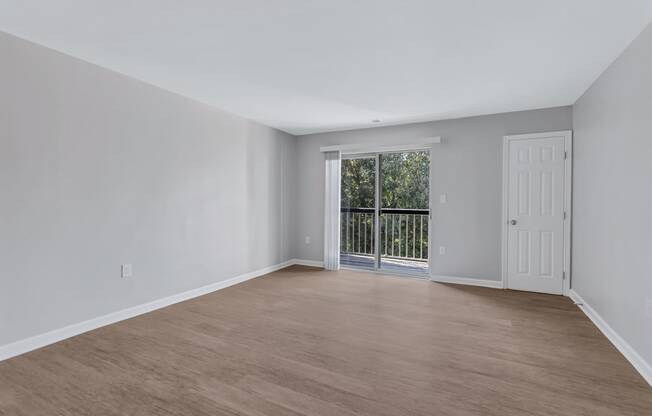 an empty living room with a door to a balcony