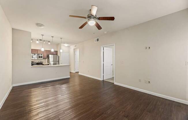 A room with a ceiling fan and wooden flooring.
