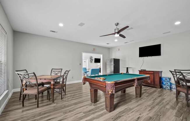 A room with a pool table and a television.