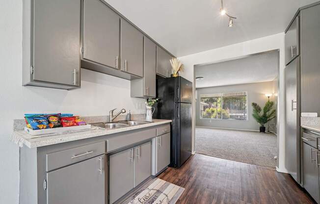 A kitchen with a black refrigerator and wooden floors.