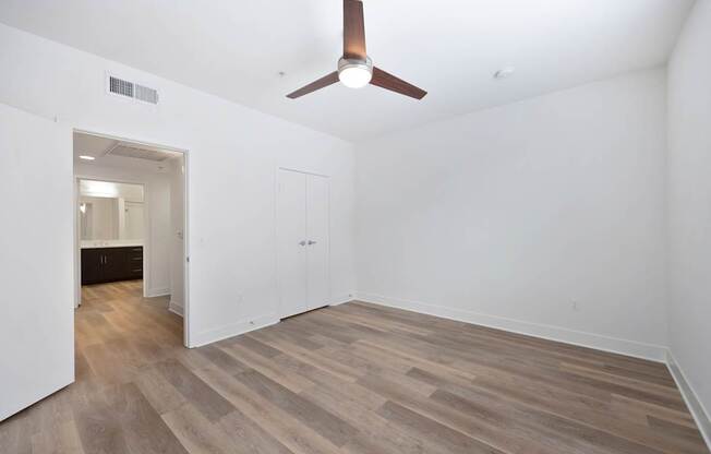 A room with a ceiling fan and wood flooring.