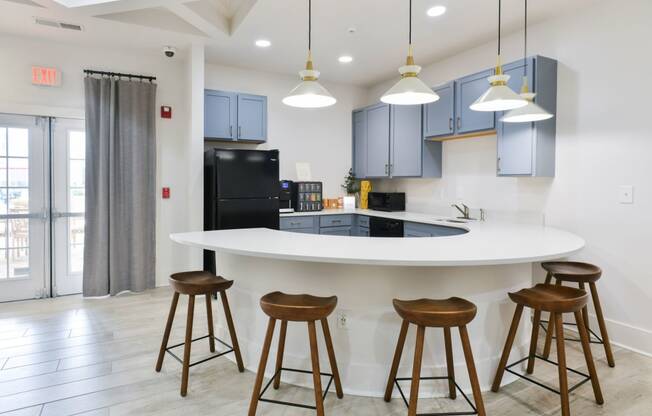 a kitchen with a large island with bar stools and blue cabinets