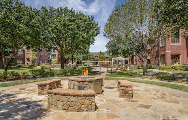 A stone fire pit sits in the middle of a courtyard.