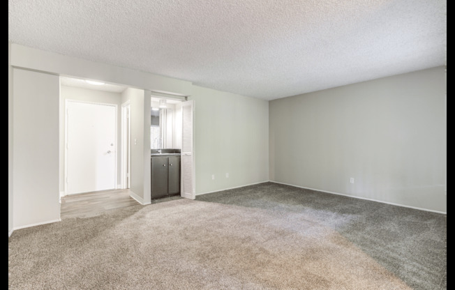 A room with a carpeted floor and a window with blinds.