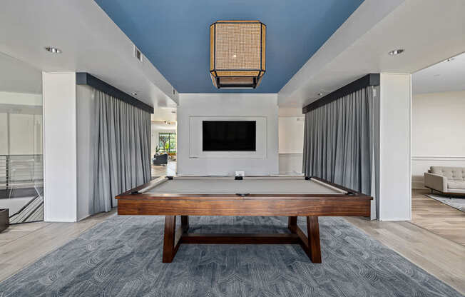 A billiard table is in the middle of a room with a television.