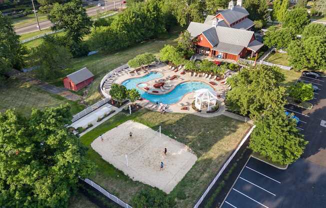 A large red building with a pool and a sandy area in front.