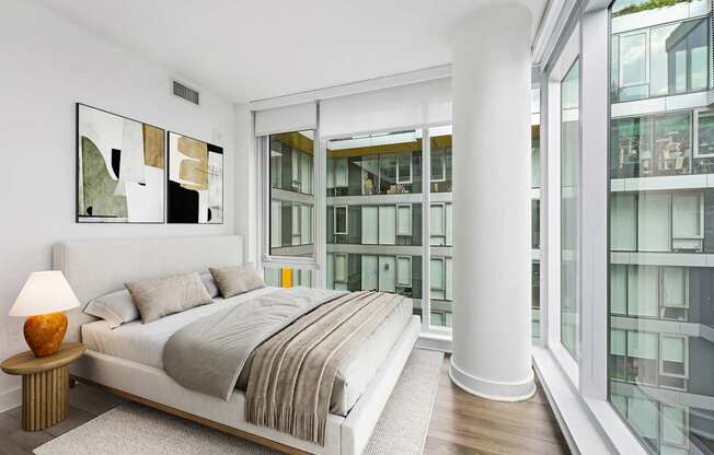 A bedroom with a large bed and a lamp on a side table.