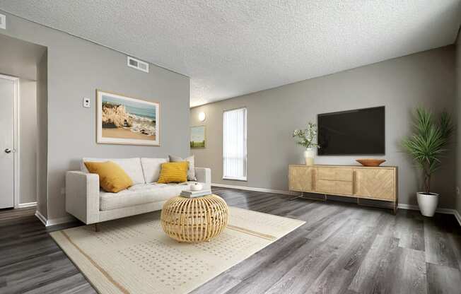 A living room with a white couch, a wicker table, and a painting on the wall.