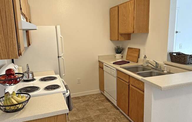 Bridgeside Landing Apartments in Taylorsville, Utah, Kitchen with wood cabinets, stove, fridge, dishwasher and double sink.