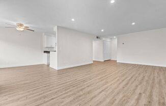 the living room and kitchen of an empty house with a ceiling fan