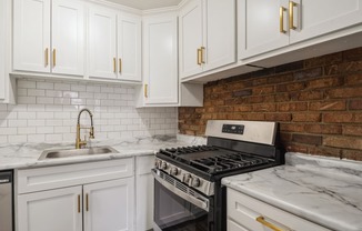 a kitchen with white cabinets and a brick wall