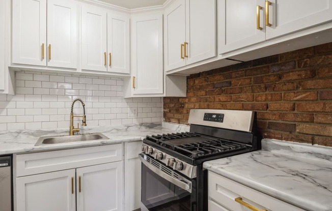 a kitchen with white cabinets and a brick wall