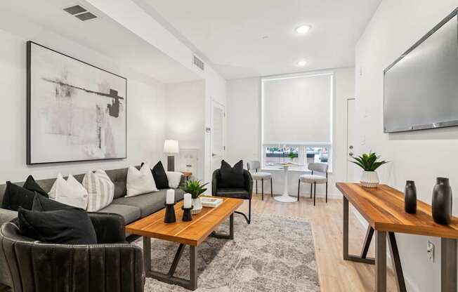 A modern living room with a grey couch, a wooden coffee table, and a large abstract painting on the wall.