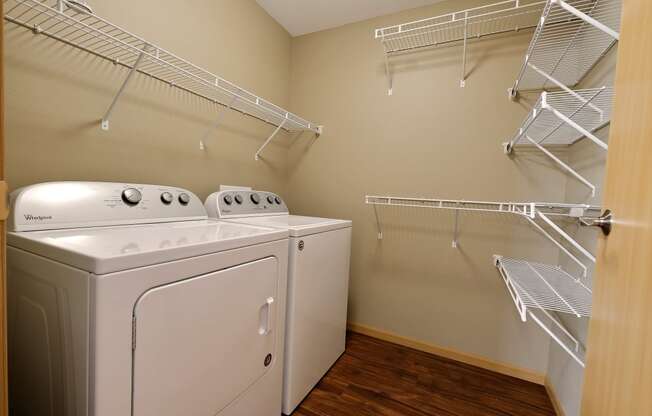 a spacious laundry room with a washer and dryer and a closet with shelves. Fargo, ND Urban Plains Apartments