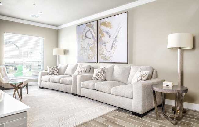 A living room with a grey couch and a painting on the wall.