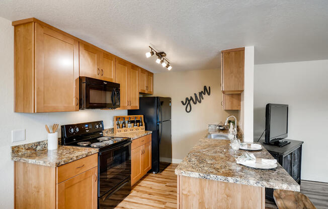 Apartments Happy Valley - Sunnyside Village Apartments Kitchen with Matching Black Appliances, Large Island, and Granite Style Countertops