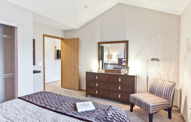 a bedroom with a bed and a chair and a dresser