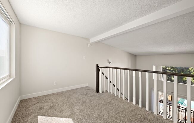 the upstairs loft of a house with carpeted stairs and a window