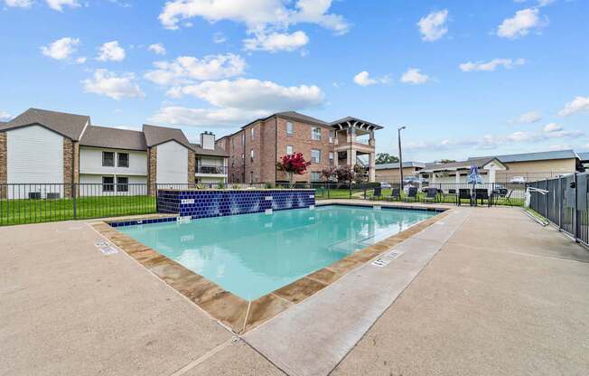 A swimming pool surrounded by a concrete floor and a fence.