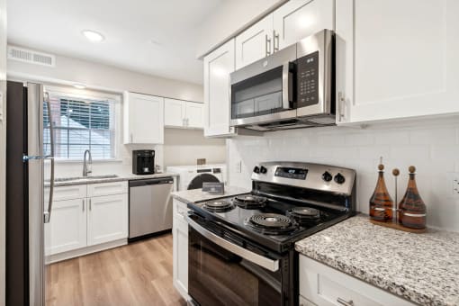 a kitchen with white cabinets and black appliances