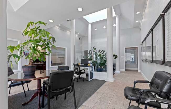 an office with black chairs and a table and pillars