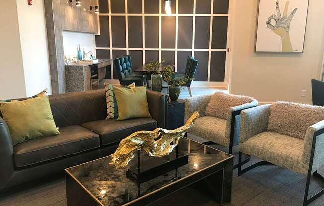 A living room with a black couch, a coffee table, and a painting on the wall.